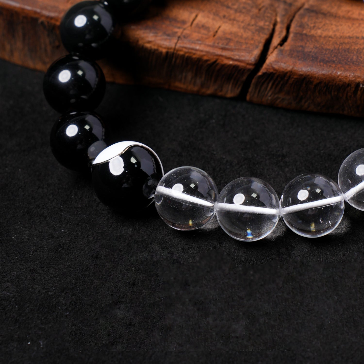 Macro close-up on the central black bead with a white Yin-Yang (Tai Chi) motif on Nuwa Stone's "Clarity & Shadow Balance" bracelet, showing its prominent design between clear quartz and silver obsidian beads.