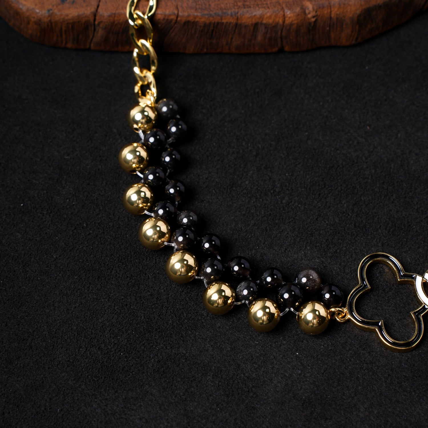 Detailed close-up of the beaded section of Nuwa Stone's "East-West Reverie" necklace, showcasing the alternating pattern of black onyx and gold-plated spherical beads, highlighting their luster.