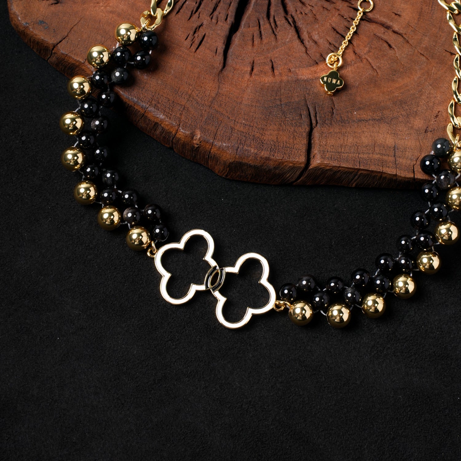 Close-up of the central interconnected gold-plated quatrefoil charms and the adjustable chain clasp with a small Nuwa Stone logo tag on the "East-West Reverie" necklace, emphasizing the intricate details.
