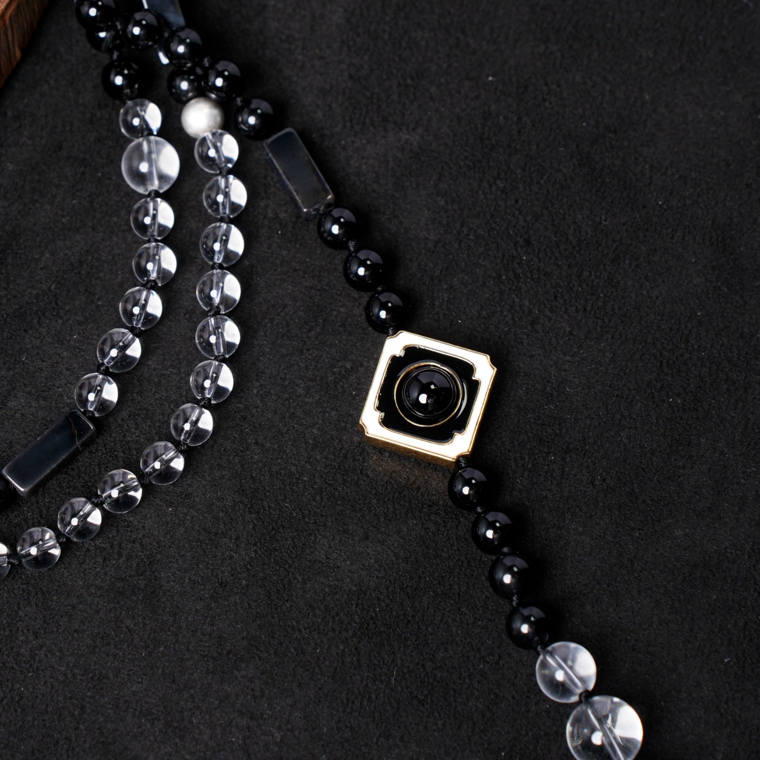 Detailed close-up of the central gold-plated square pendant with a black onyx bead, from Nuwa Stone's "Four Symbols Begonia" necklace, highlighting its intricate design against the beaded strands.
