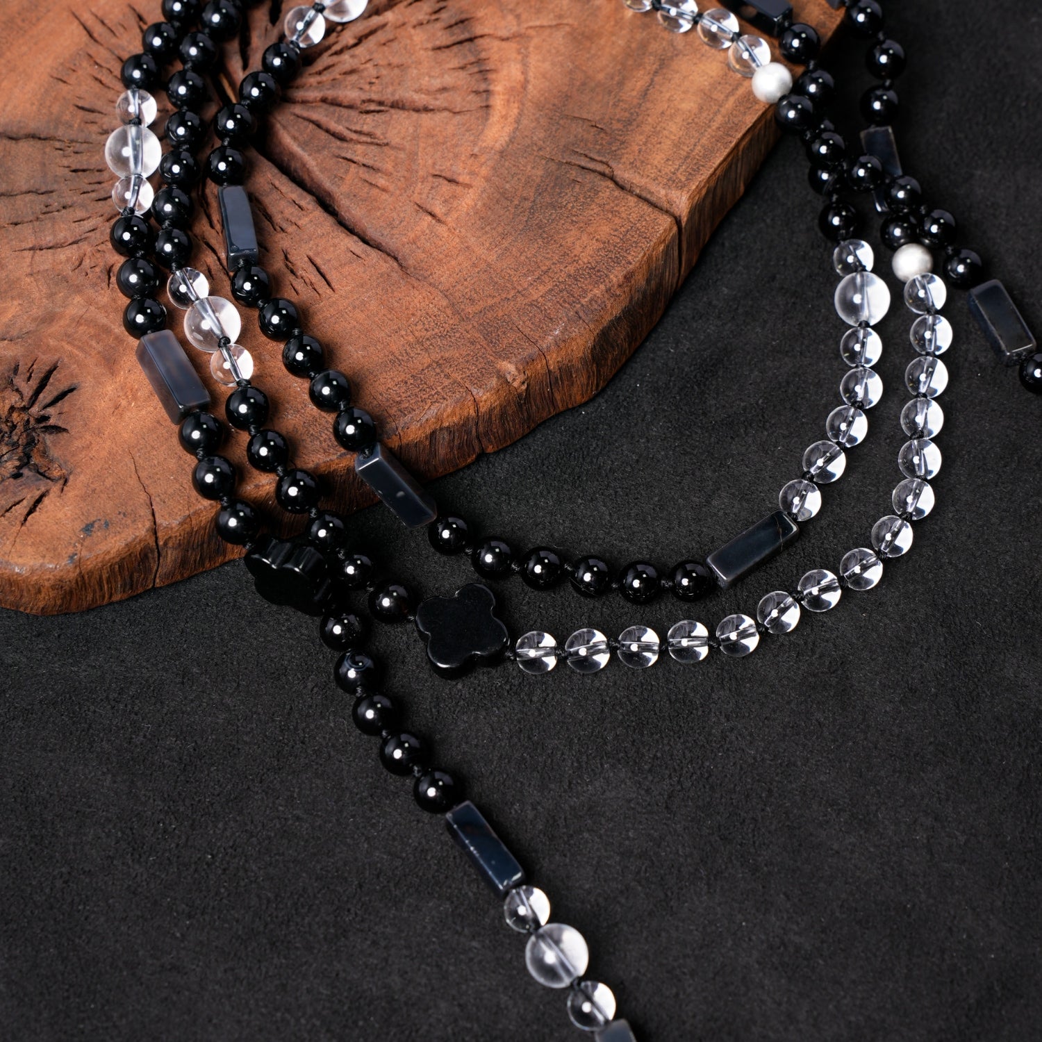 Detailed close-up of the beads on Nuwa Stone's "Four Symbols Begonia" necklace, showcasing faceted clear quartz, polished black onyx, rectangular black agate spacers, and quatrefoil-shaped black onyx charms.