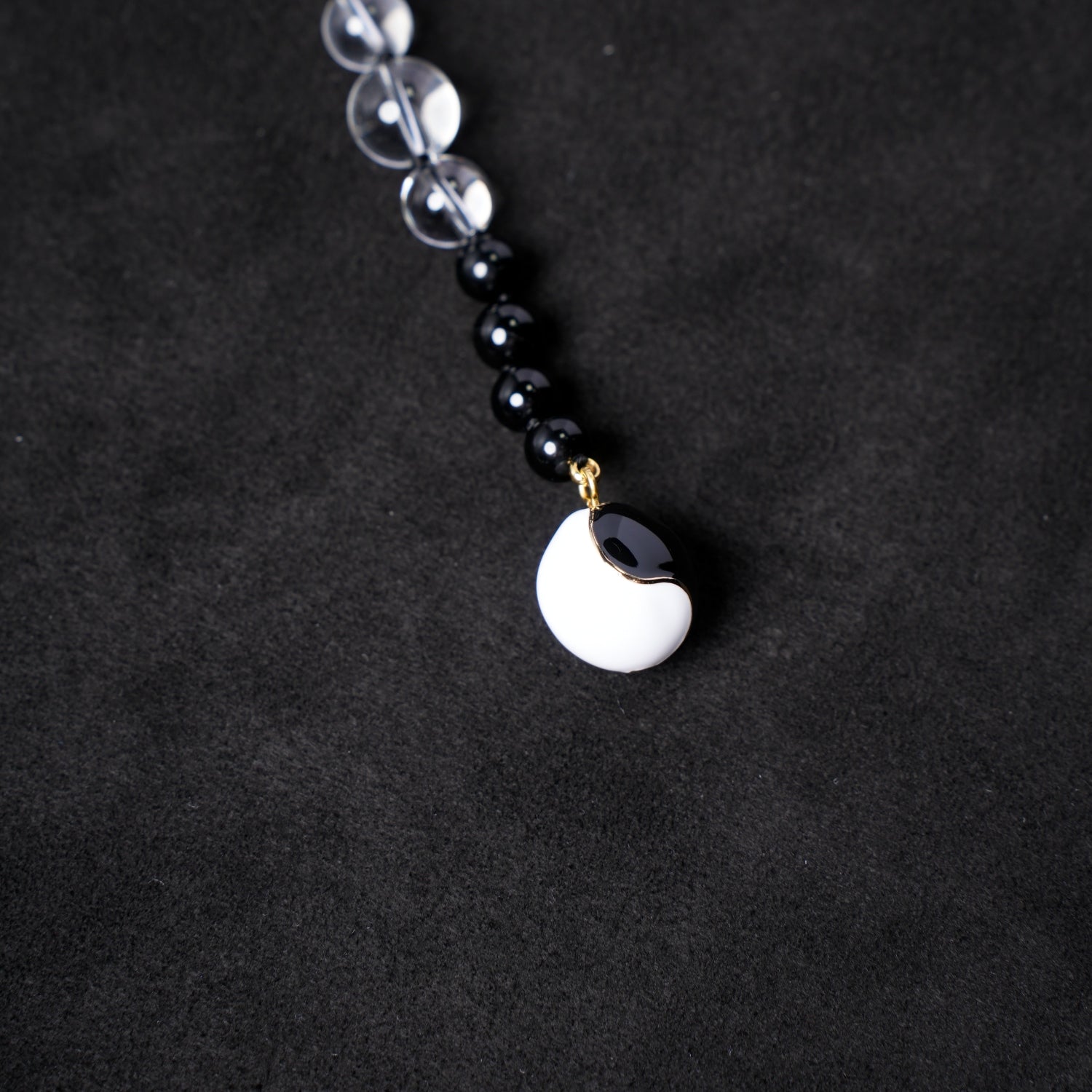 Close-up of the black and white yin-yang shaped charm from Nuwa Stone's "Four Symbols Begonia" necklace, elegantly contrasting with the surrounding black onyx and clear quartz beads.