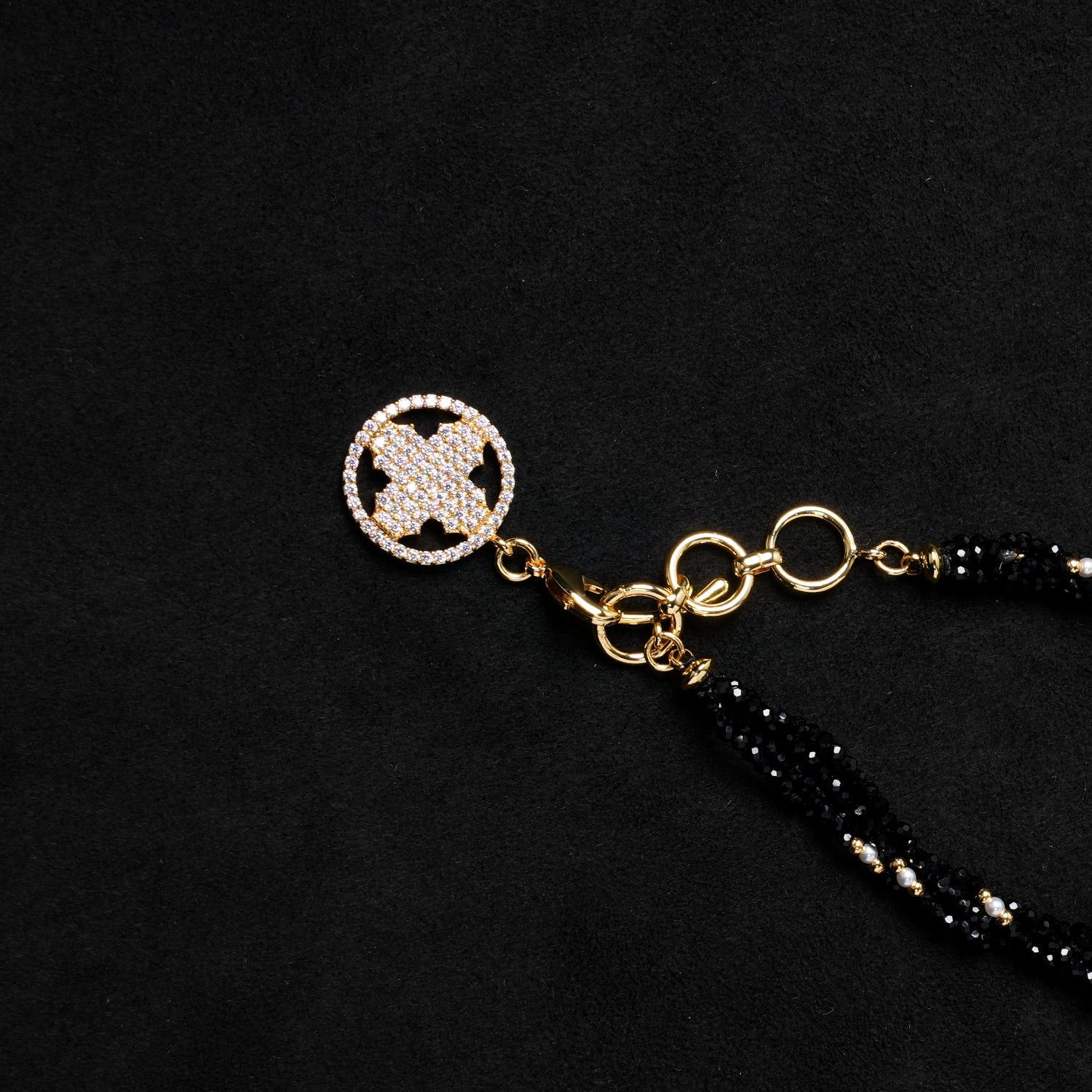 Close-up of the gold-plated adjustable clasp and the sparkling zirconia-paved quatrefoil charm on the end of Nuwa Stone's "Ink Begonia Cascading Snow" necklace, highlighting the intricate details of the adjuster.