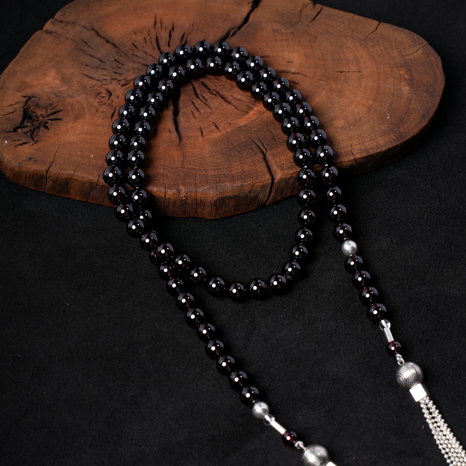 Detailed close-up of the multiple strands of deep red garnet beads, interspersed with lustrous sterling silver and black onyx beads, from Nuwa Stone's "Twilight Pearl Radiance" necklace.